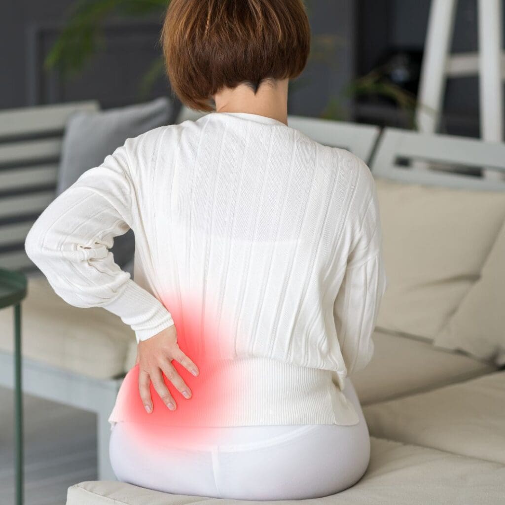 Woman experiencing low back pain trying to determine if it is muscular or organ issue